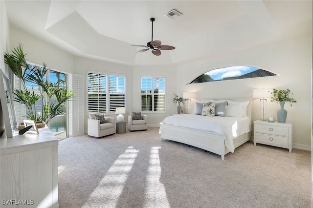 bedroom with access to outside, light colored carpet, ceiling fan, and a tray ceiling