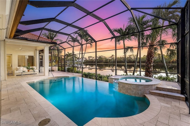 pool at dusk featuring a water view, ceiling fan, a lanai, an in ground hot tub, and a patio area