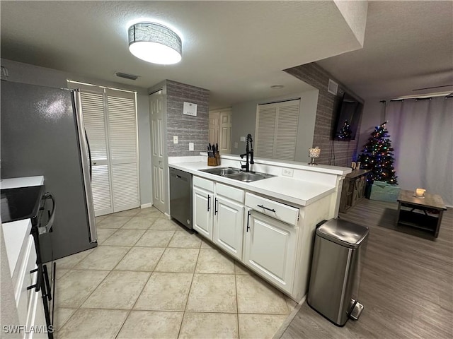 kitchen featuring stainless steel dishwasher, sink, white cabinetry, and kitchen peninsula