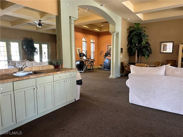 interior space with beam ceiling, ceiling fan, sink, coffered ceiling, and dark colored carpet