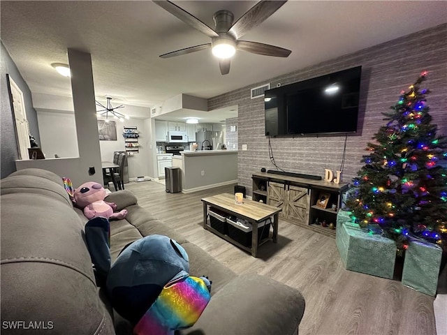 living room featuring light hardwood / wood-style flooring, ceiling fan, and sink