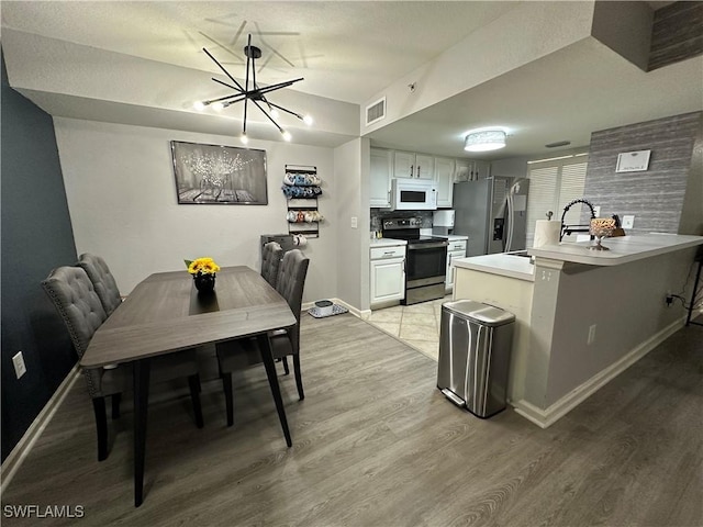 kitchen with kitchen peninsula, electric range, white cabinets, and stainless steel refrigerator with ice dispenser