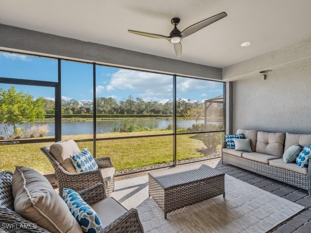 sunroom featuring ceiling fan and a water view