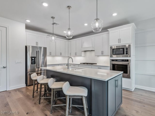 kitchen with white cabinets, decorative light fixtures, custom range hood, and stainless steel appliances