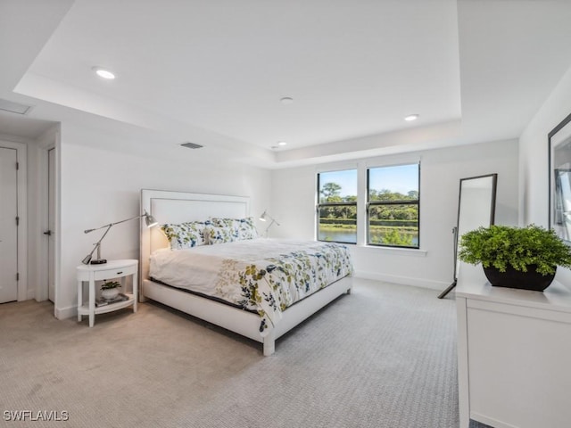 bedroom featuring light colored carpet and a tray ceiling