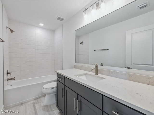 full bathroom featuring tiled shower / bath, vanity, and toilet