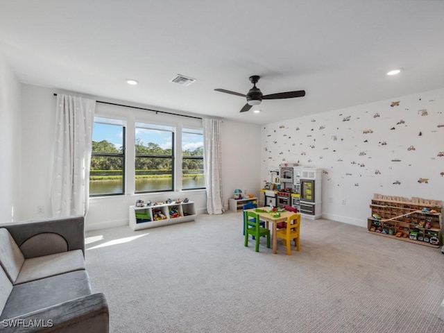 recreation room featuring carpet flooring, ceiling fan, and a water view