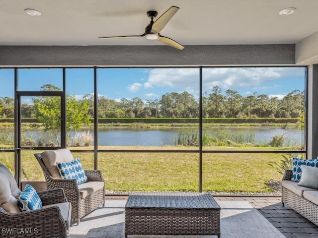 sunroom / solarium with ceiling fan and a water view