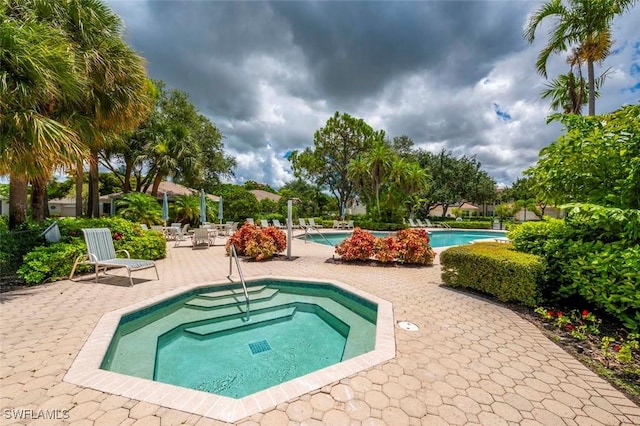 view of swimming pool with a patio area and a hot tub