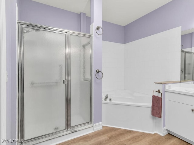 bathroom with wood-type flooring, vanity, and shower with separate bathtub