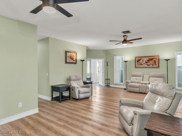 living room featuring light wood-type flooring, baseboards, visible vents, and ceiling fan