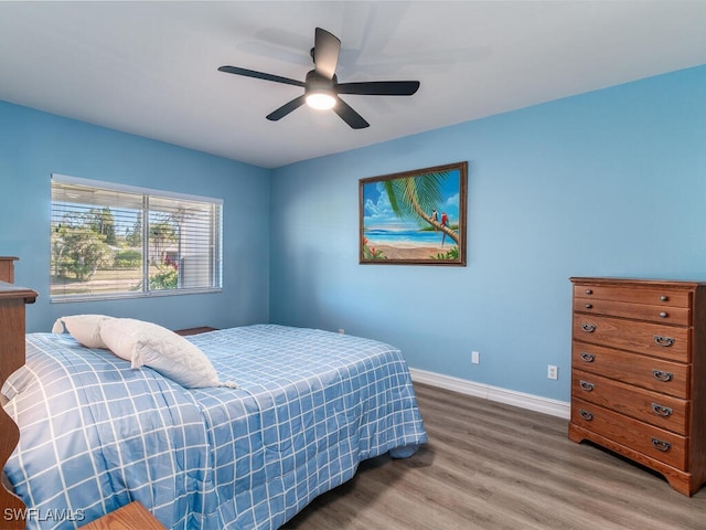 bedroom with a ceiling fan, baseboards, and wood finished floors