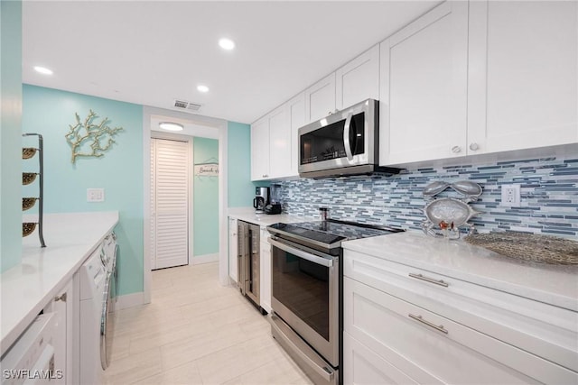 kitchen with tasteful backsplash, white cabinetry, and appliances with stainless steel finishes