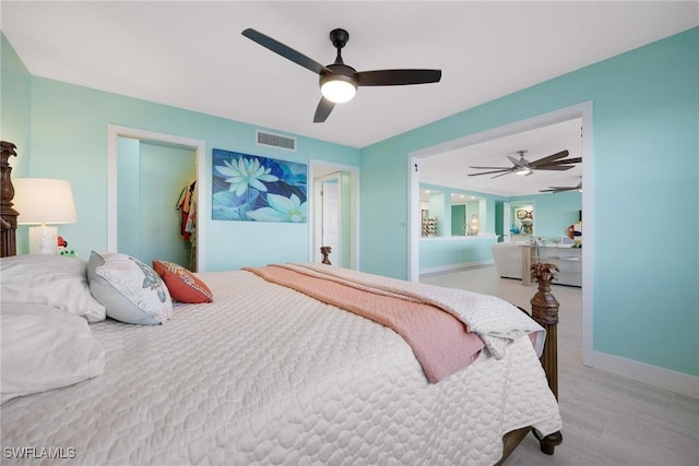 bedroom with ceiling fan, light wood-type flooring, a walk in closet, and a closet