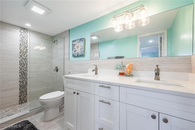 bathroom with backsplash, toilet, tiled shower, vanity, and tile walls