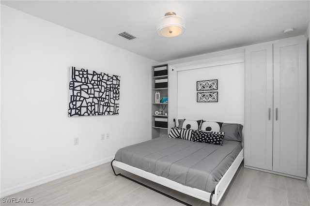 bedroom featuring light wood-style floors, visible vents, and baseboards