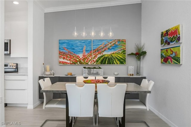 dining room featuring light wood-type flooring, baseboards, and crown molding