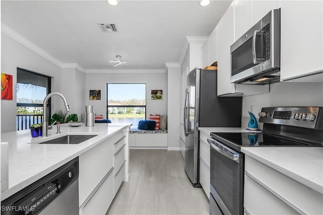 kitchen featuring a sink, visible vents, white cabinets, ornamental molding, and appliances with stainless steel finishes