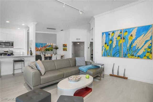 living area featuring crown molding, visible vents, light wood-style flooring, track lighting, and baseboards