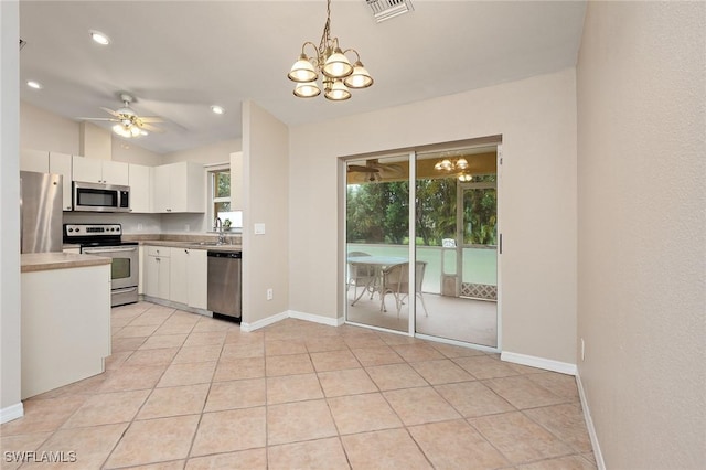 kitchen with ceiling fan with notable chandelier, stainless steel appliances, sink, white cabinets, and hanging light fixtures