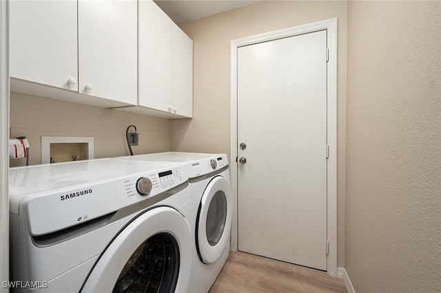 laundry room featuring cabinets, light hardwood / wood-style floors, and washer and clothes dryer