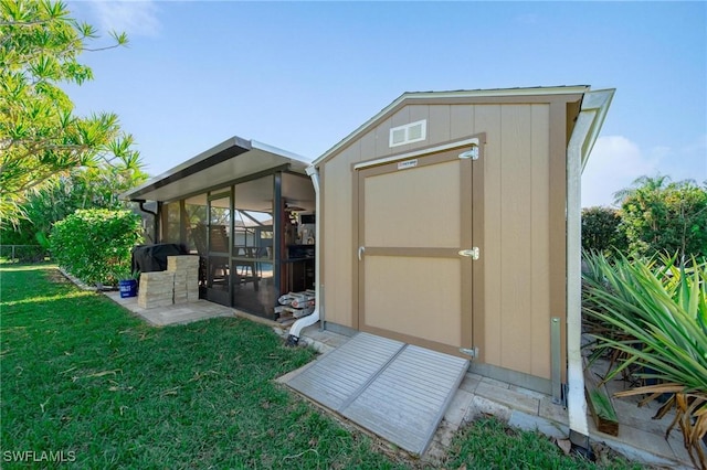 view of outdoor structure featuring a sunroom and a lawn