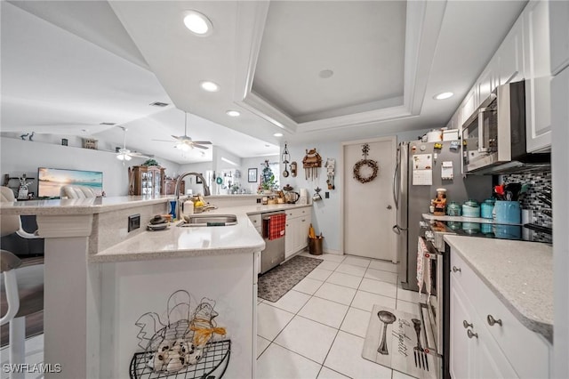 kitchen featuring sink, kitchen peninsula, a breakfast bar, white cabinets, and appliances with stainless steel finishes