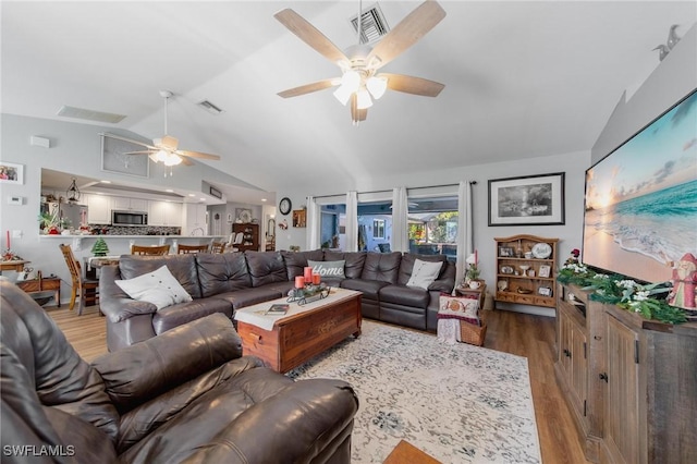 living room with ceiling fan, light wood-type flooring, and vaulted ceiling