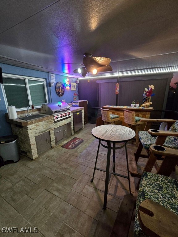 exterior space featuring ceiling fan, wet bar, and a textured ceiling