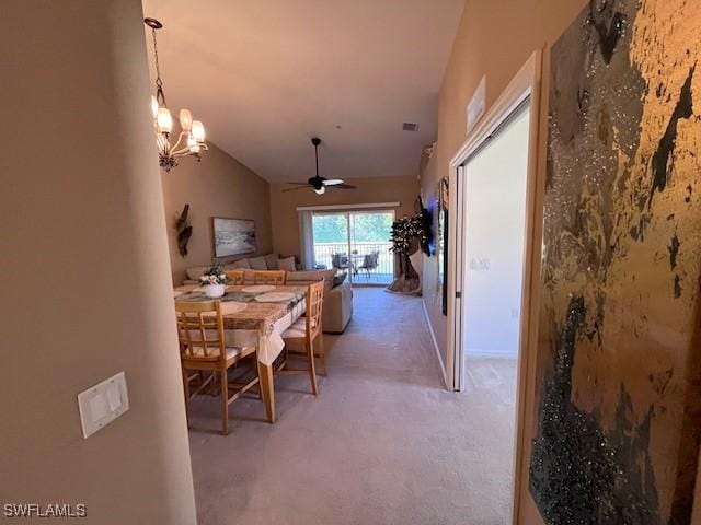 carpeted dining room with ceiling fan with notable chandelier