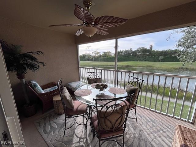 sunroom with ceiling fan and a water view