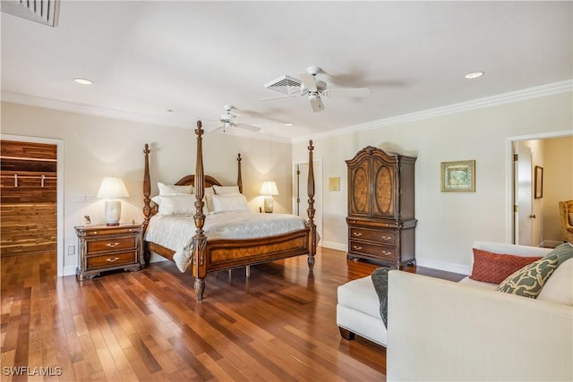 bedroom featuring ceiling fan, dark wood-type flooring, crown molding, a walk in closet, and a closet