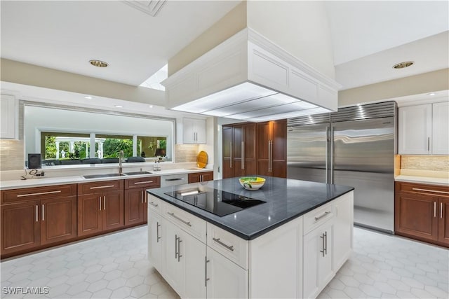 kitchen featuring sink, built in refrigerator, black electric cooktop, decorative backsplash, and light tile patterned floors