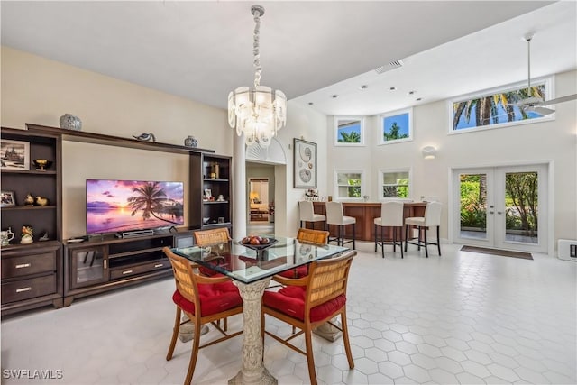 dining area with french doors, a towering ceiling, and a chandelier