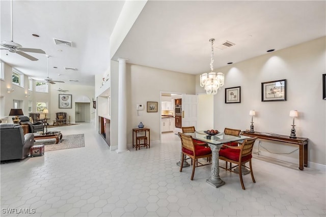 dining space featuring decorative columns and ceiling fan with notable chandelier