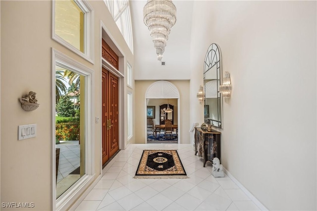 hall featuring a high ceiling, light tile patterned floors, and an inviting chandelier