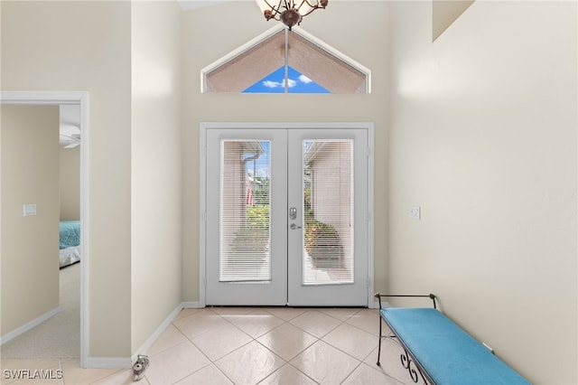 entryway with light tile patterned flooring, an inviting chandelier, a high ceiling, and french doors