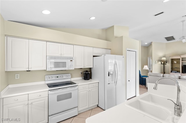 kitchen with white appliances, vaulted ceiling, sink, light tile patterned floors, and white cabinetry