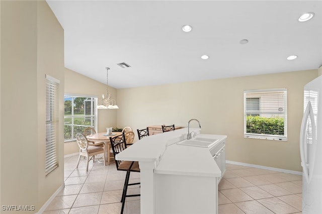 kitchen with pendant lighting, sink, vaulted ceiling, light tile patterned floors, and a chandelier