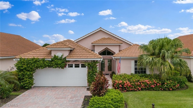 mediterranean / spanish-style house featuring a garage and a front lawn