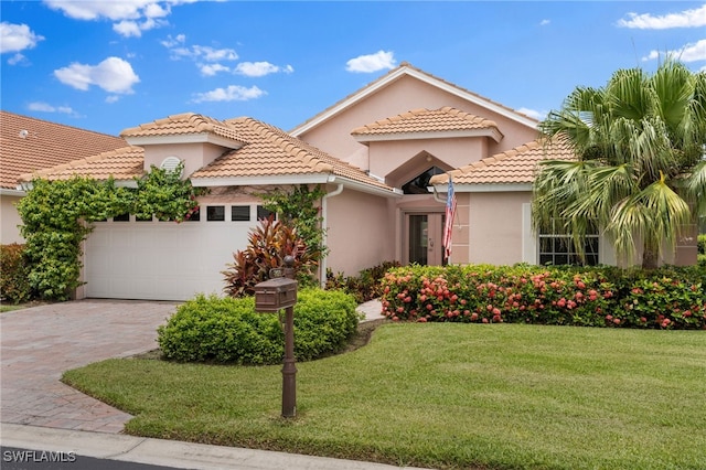 mediterranean / spanish home featuring a front yard and a garage