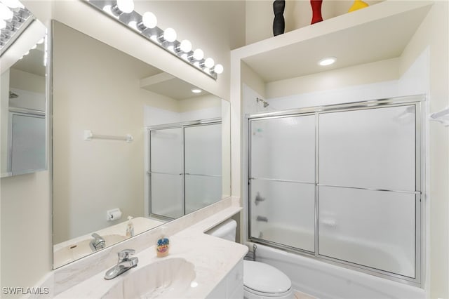 full bathroom with combined bath / shower with glass door, toilet, and vanity