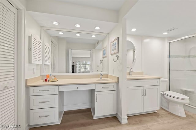 bathroom featuring hardwood / wood-style floors, vanity, toilet, and a shower with shower door