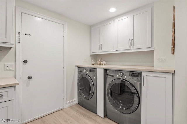 clothes washing area featuring cabinets, independent washer and dryer, and light wood-type flooring