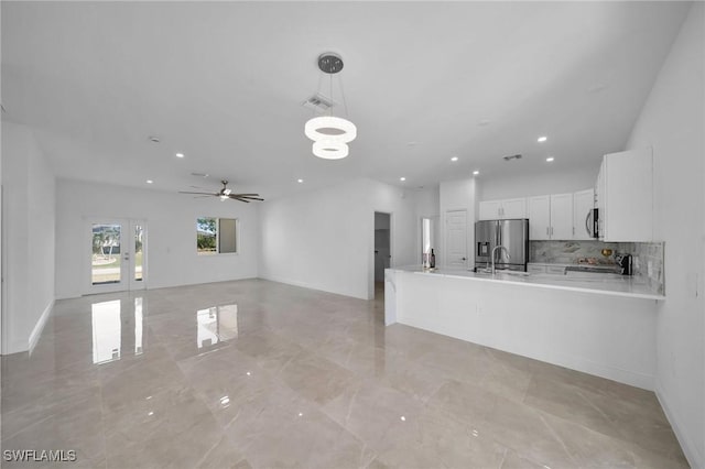 kitchen featuring white cabinets, stainless steel refrigerator with ice dispenser, hanging light fixtures, tasteful backsplash, and kitchen peninsula