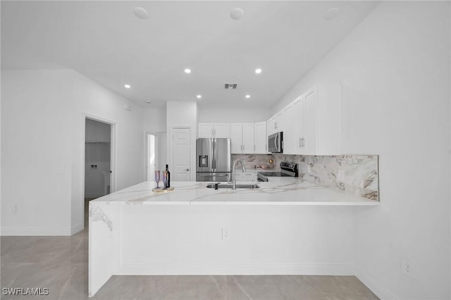 kitchen with white cabinets, sink, light stone counters, kitchen peninsula, and stainless steel appliances