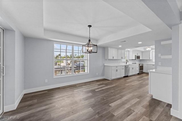 kitchen featuring sink, wood-type flooring, white cabinets, ceiling fan with notable chandelier, and appliances with stainless steel finishes