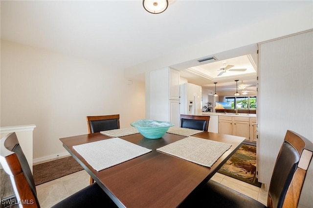 dining room featuring ceiling fan, sink, a raised ceiling, light tile patterned floors, and ornamental molding