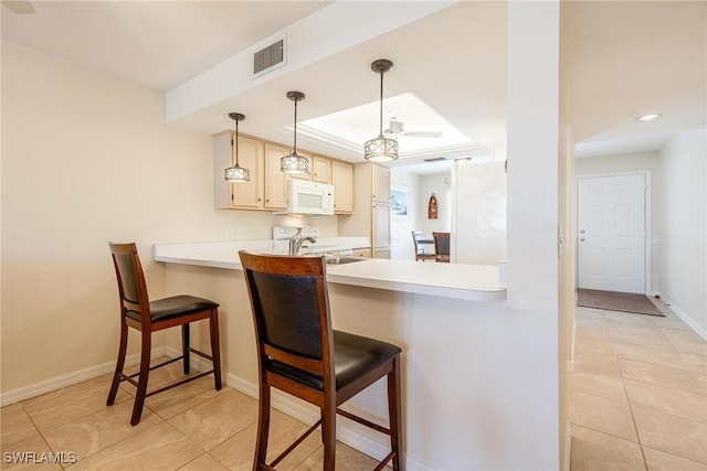 kitchen with a kitchen bar, light tile patterned floors, pendant lighting, and white appliances