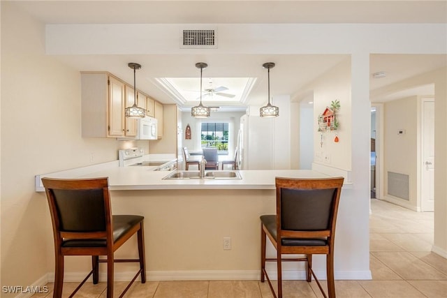 kitchen with kitchen peninsula, a kitchen bar, white appliances, and hanging light fixtures